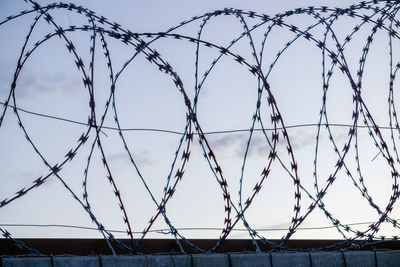 Low angle view of barbed wire fence against sky