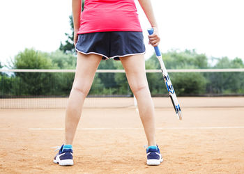 Low section of woman playing tennis on court