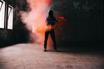 Man holding distress flare while standing in abandoned room
