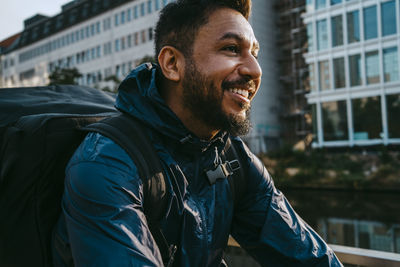 Smiling food delivery person with backpack in city