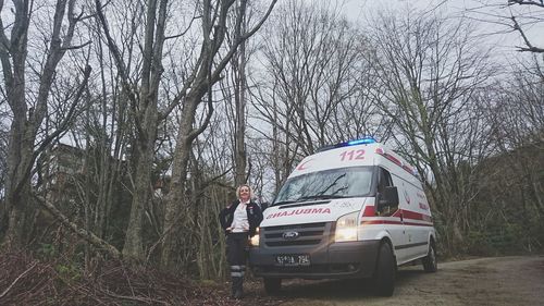 Car on bare trees against sky
