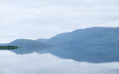 Scenic view of lake by mountains against sky