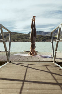 Sportswoman doing sirsasana on jetty