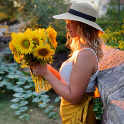 Midsection of woman holding yellow flowering plant