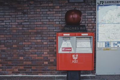 Close-up of telephone booth against brick wall