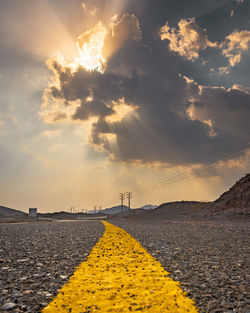 Surface level of yellow road against sky during sunset
