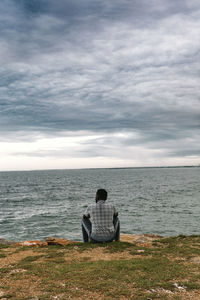 Rear view of man sitting on seat against sea