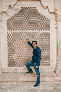 Full length portrait of young man standing against building