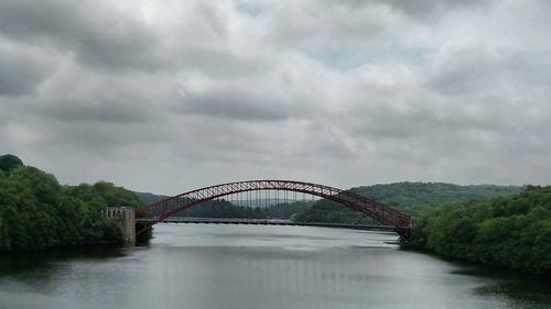 Bridge over river against cloudy sky
