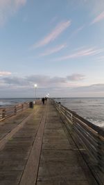 Pier over sea against sky during sunset