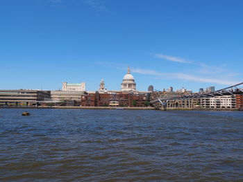 View of river and buildings against blue sky