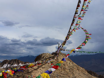 Low angle view of multi colored flags on mountain against sky