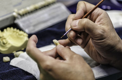 Cropped hands of person cleaning dentures in clinic