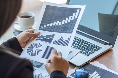 Cropped hands of businesswoman using mobile phone in office