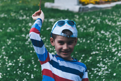 Portrait of boy aiming with plant on field
