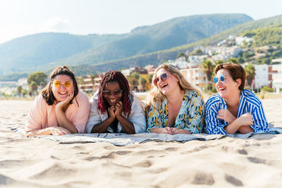 Portrait of smiling friends sitting at beach