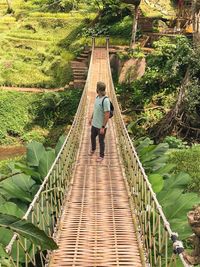 Rear view of woman walking on footbridge