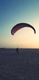 Silhouette person paragliding against clear sky