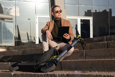 Young handsome man working as graphic designer on his tablet with an electric scooter