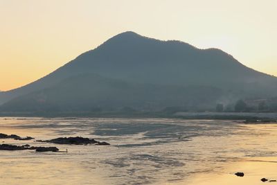 Scenic view of sea and mountains against sky during sunset