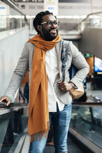 Smiling man with backpack standing on escalator