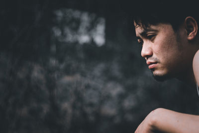 Close-up portrait of young man looking away outdoors