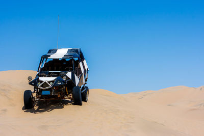 Bicycle on desert against clear blue sky