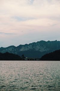 Scenic view of lake by silhouette mountains against sky