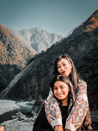 Portrait of female friends standing against mountains
