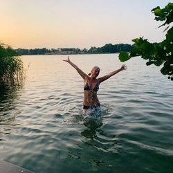 Full length of shirtless man in lake against sky