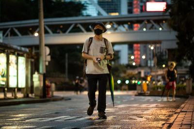 Rear view of man standing on illuminated street at night