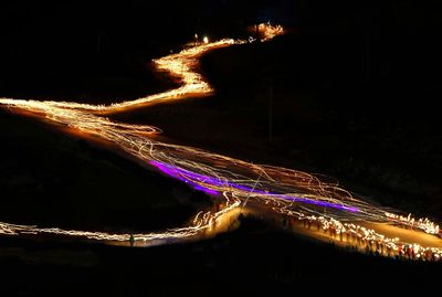 Light trails on road against sky at night