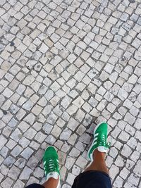 Low section of woman standing on cobblestone street