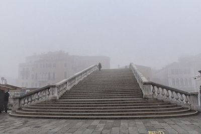 Staircase amidst buildings in city against sky during winter