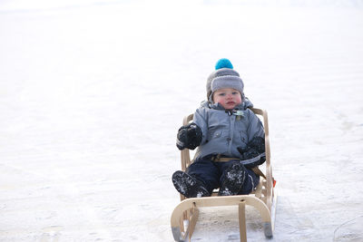 Little boy sitting in a sleigh. cute little boy sitting on her sledge in winter day. 