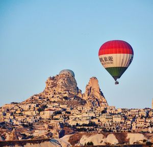 Hot air balloon flying over rock against clear sky