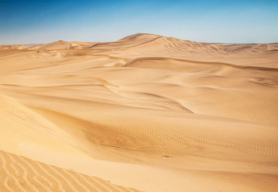 Sand dunes in desert against clear sky