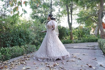 Woman standing on field against trees and plants