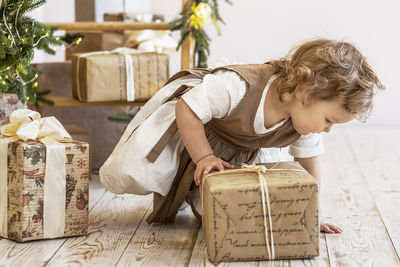 A little girl at the christmas tree with boxes of gifts. unpacking gifts, emotions,childhood
