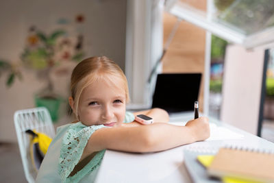 Portrait of a girl sitting on table at home