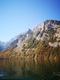 Scenic view of lake and mountains against clear blue sky