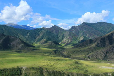 Alpine plateau with a beautiful mountain range in altai and a sky with clouds in summer