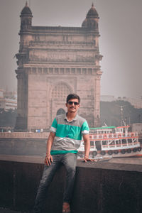 Full length of young man against sky in city near the gateway of india