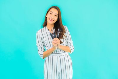 Portrait of a smiling young woman against blue background