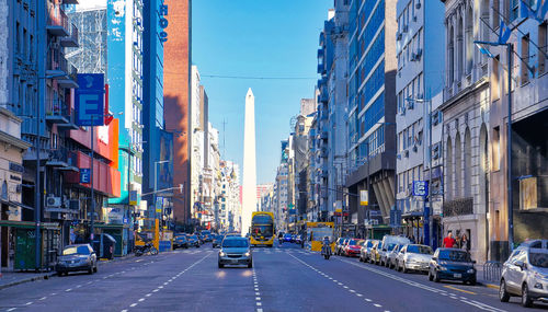 Traffic on road amidst buildings in city against sky