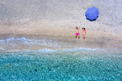 Aerial view of couple lying at beach on sunny day