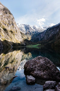 Rocks in lake by mountains against sky