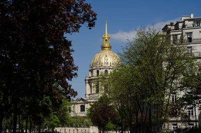 Low angle view of trees and building against sky