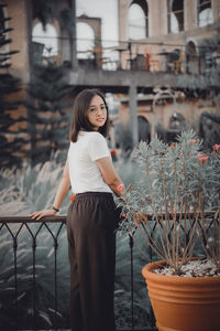 Side view of young woman standing against building