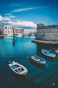 Boats in sea against buildings in city